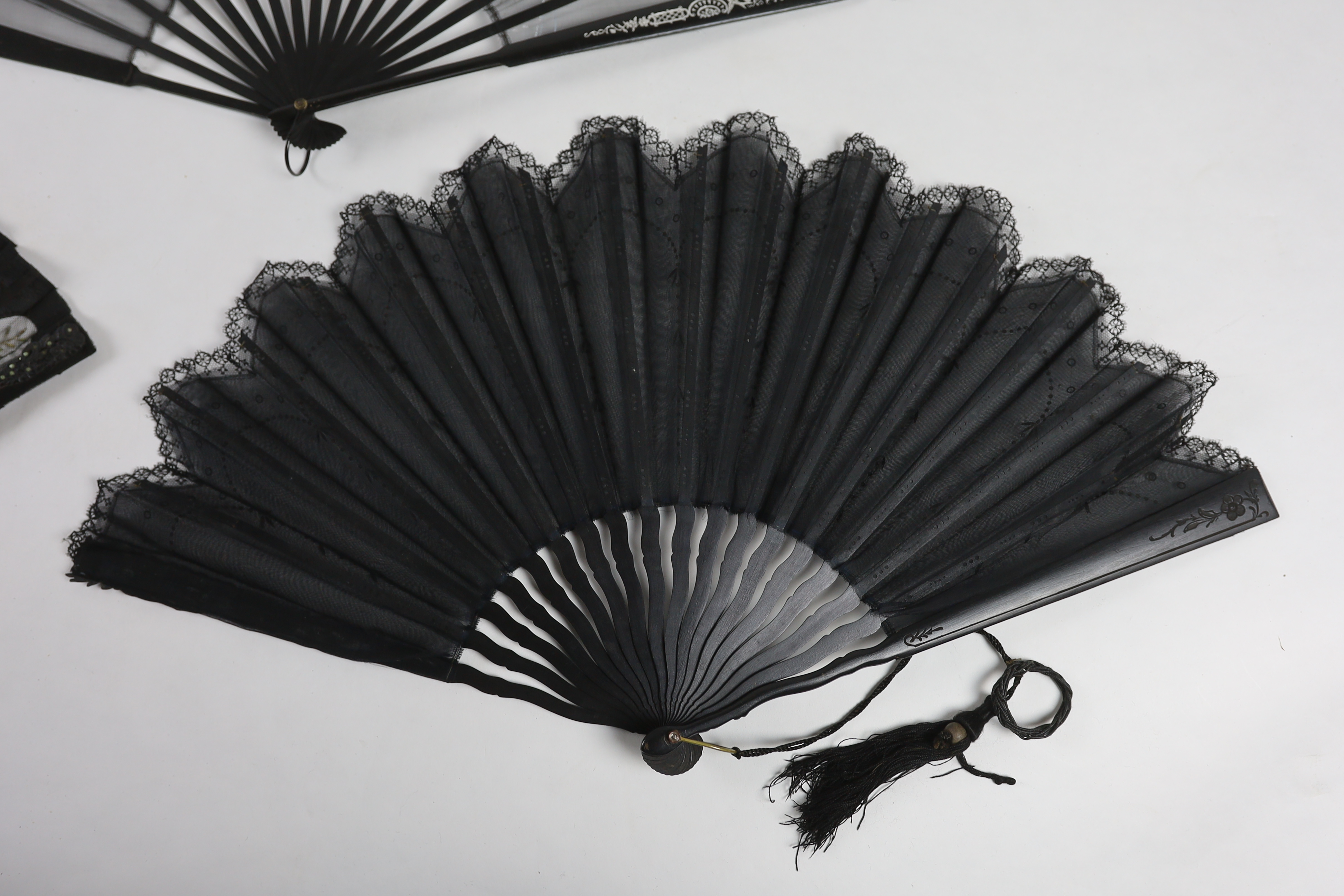 An Edwardian black silk and ornate sequin fan, a similar fan with carved ebony guards and a fine gauze fan with painted sprig and butterfly decoration (3)